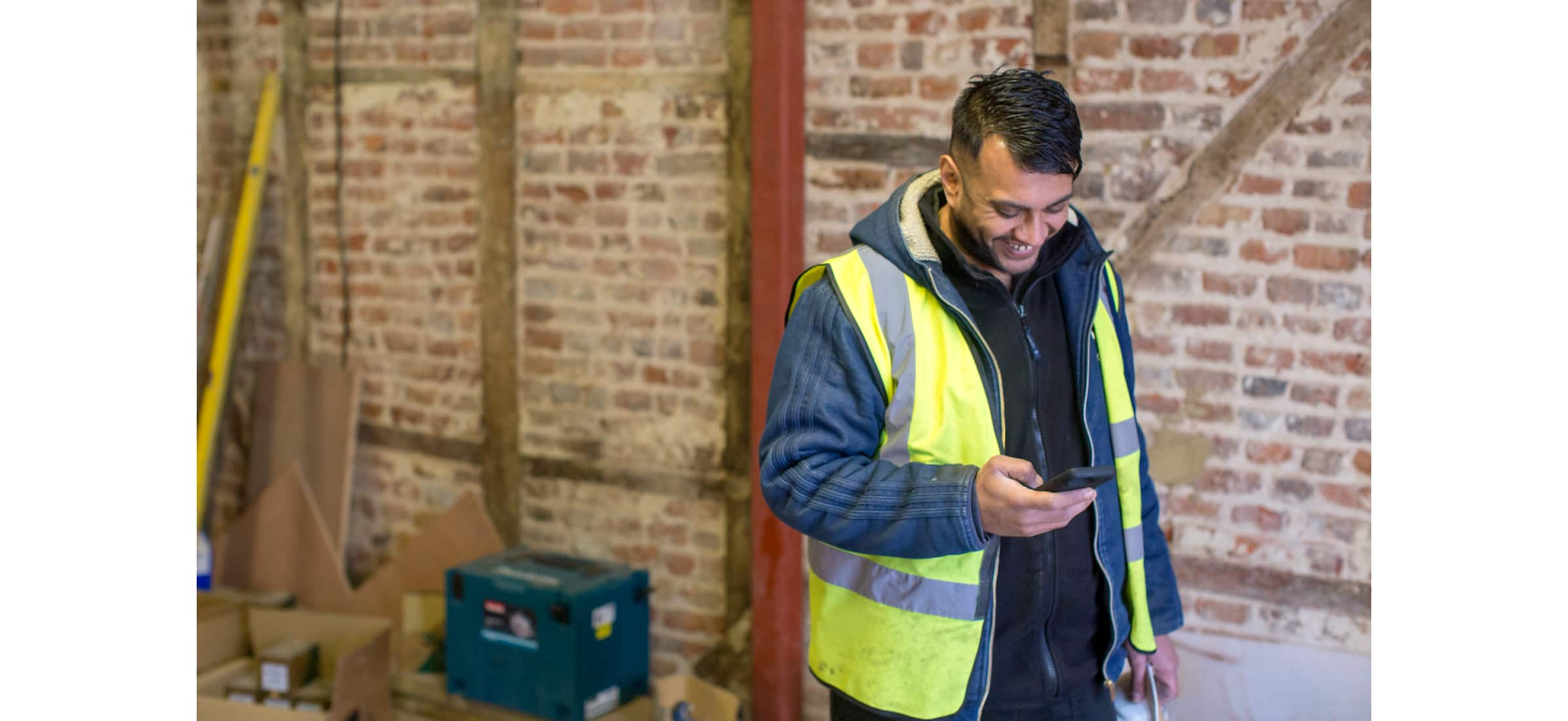 Hitesh Kanbi at a construction site checking his mobile device.